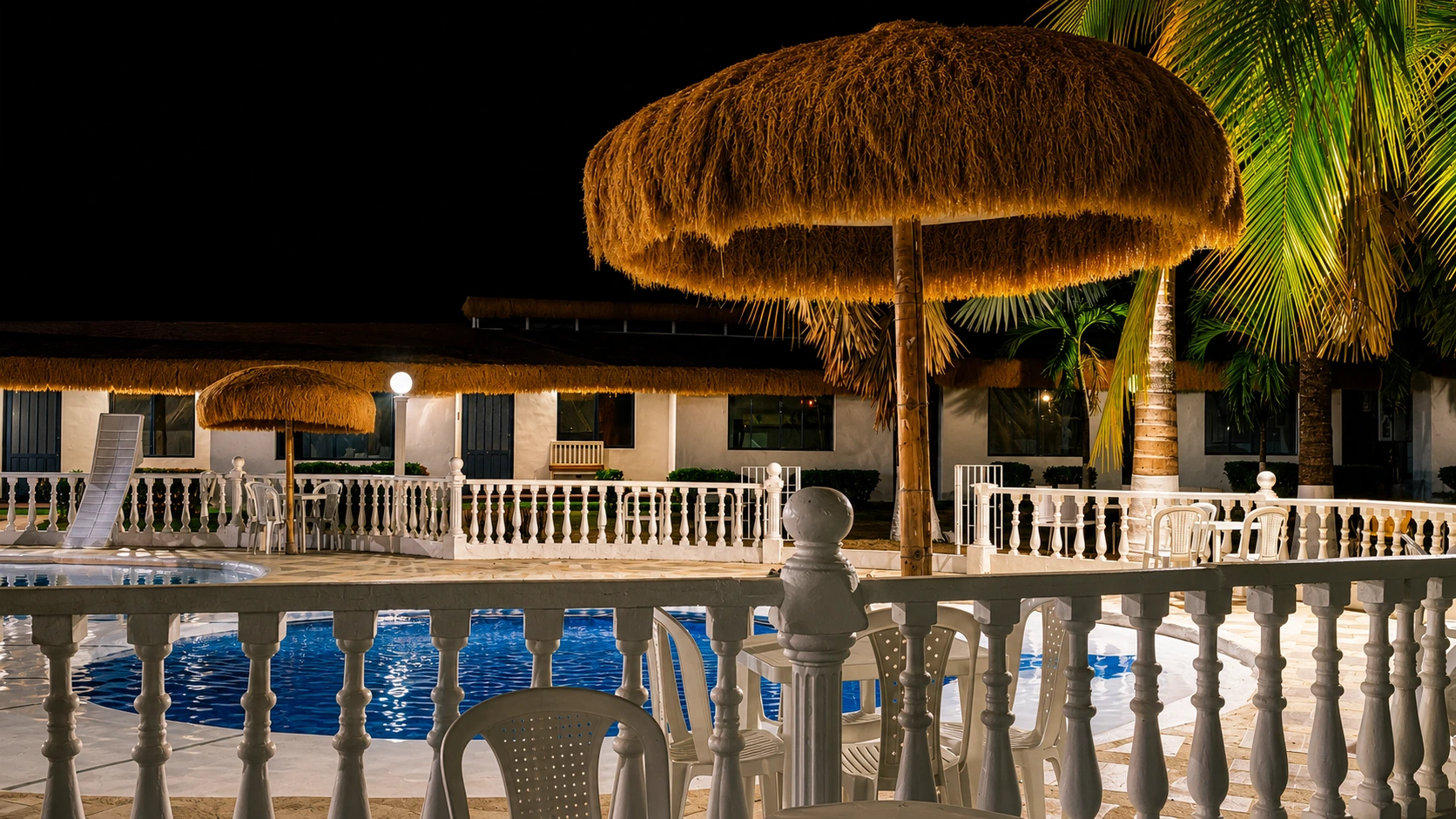Zona social con sombrilla campestre y piscina iluminada